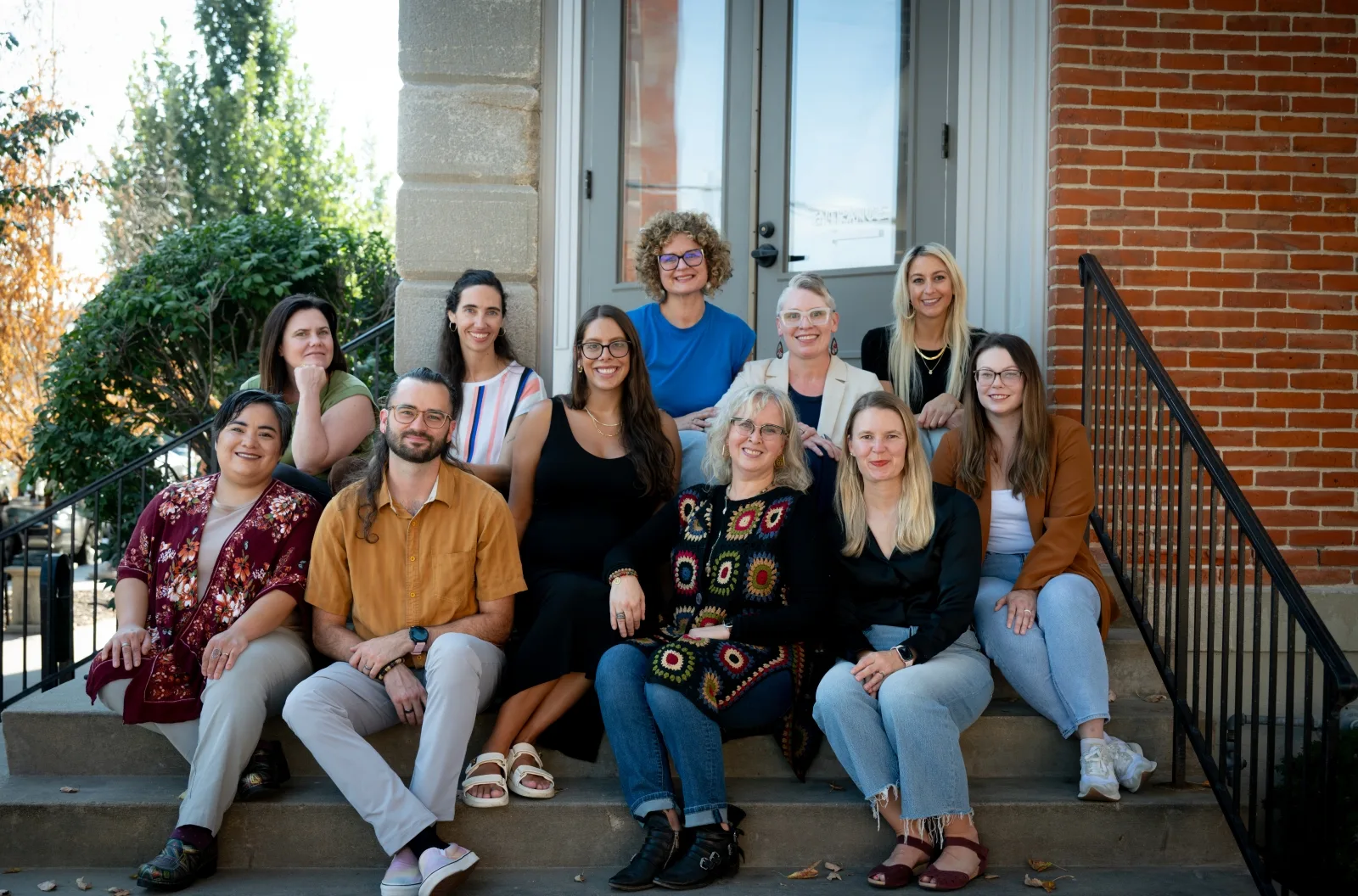 Group photo of the Integrated Community Therapists team sitting together on outdoor steps, smiling and relaxed.